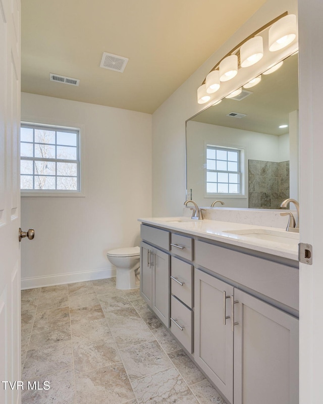 bathroom with double vanity, a healthy amount of sunlight, visible vents, and a sink