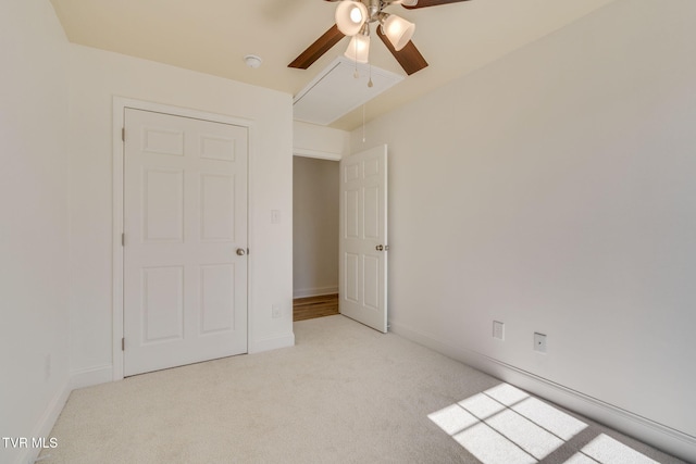 unfurnished bedroom featuring baseboards, light carpet, attic access, and a ceiling fan