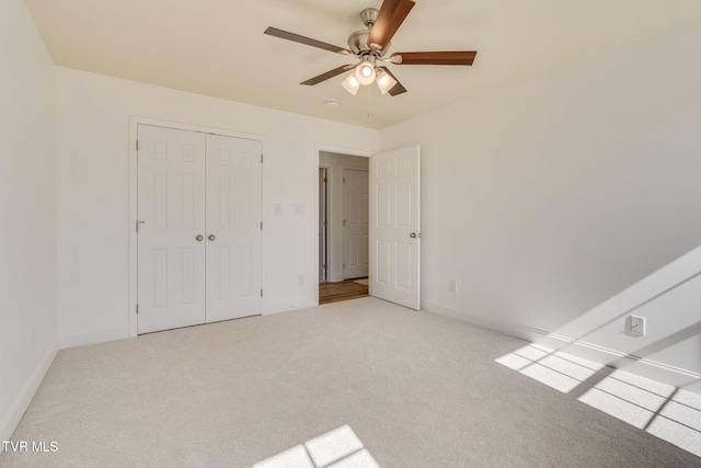 unfurnished bedroom featuring ceiling fan, baseboards, a closet, and light carpet