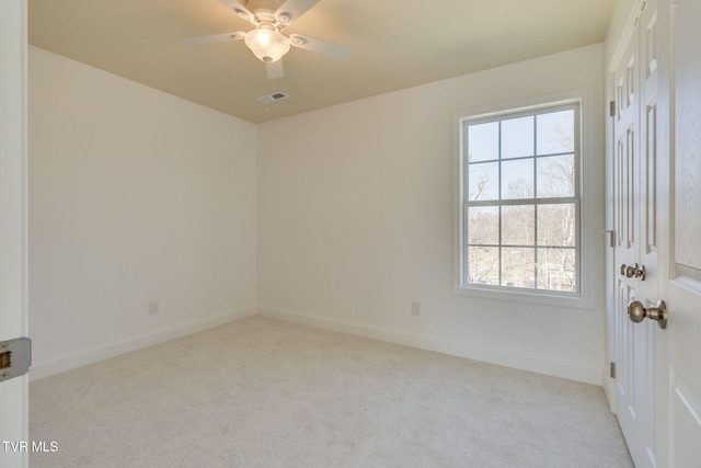 empty room with visible vents, baseboards, carpet, and a ceiling fan