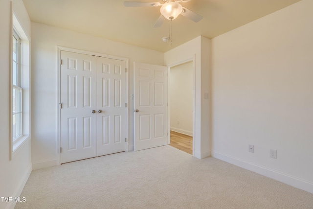 unfurnished bedroom featuring baseboards, multiple windows, a closet, and carpet flooring