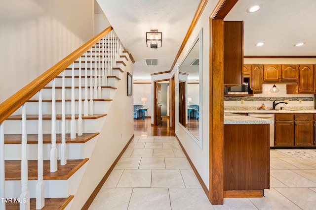 staircase featuring ornamental molding, a textured ceiling, and tile patterned flooring