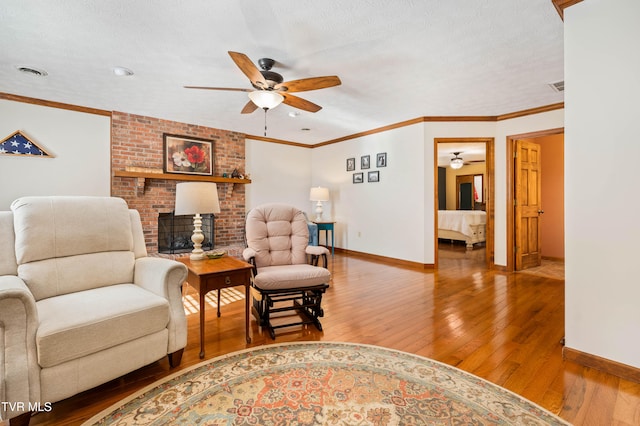 living area featuring ornamental molding, a textured ceiling, hardwood / wood-style flooring, and ceiling fan