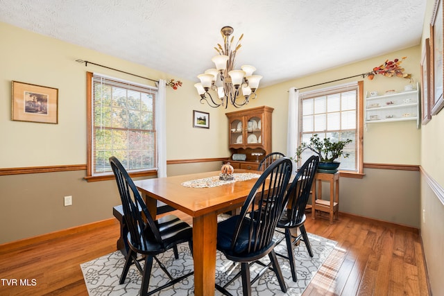 dining room featuring a textured ceiling, wood-type flooring, and a chandelier