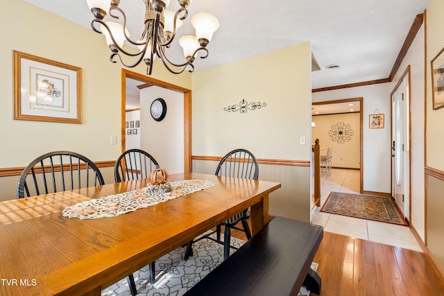 dining room with a chandelier, crown molding, and light hardwood / wood-style floors