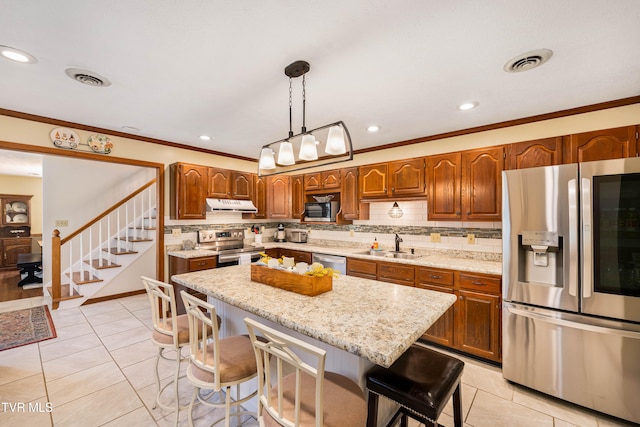 kitchen featuring a kitchen island, decorative backsplash, stainless steel appliances, sink, and pendant lighting