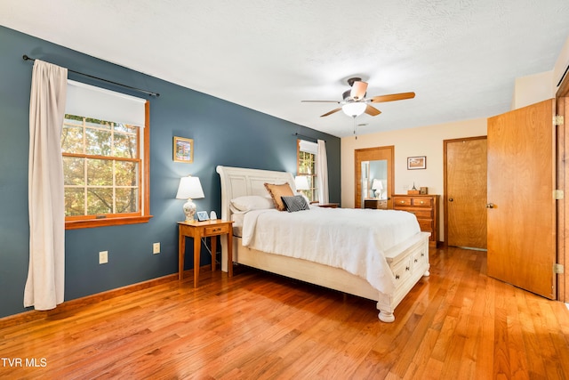 bedroom with ceiling fan, a textured ceiling, and light hardwood / wood-style floors