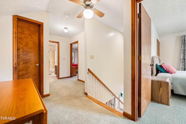 hall featuring lofted ceiling, a textured ceiling, and light colored carpet