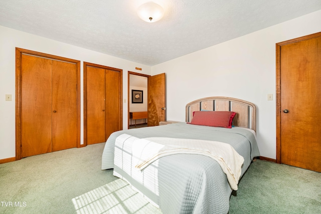 carpeted bedroom featuring a textured ceiling and multiple closets