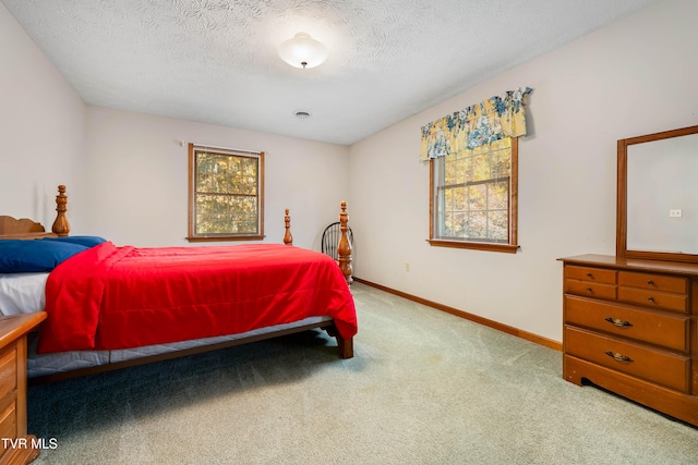 bedroom featuring light carpet and a textured ceiling