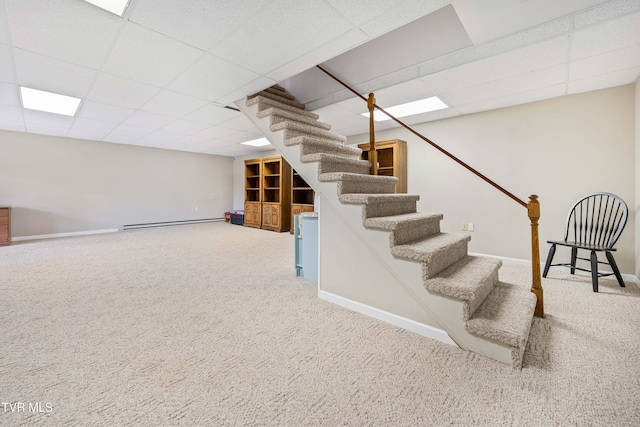 basement featuring a paneled ceiling, carpet flooring, and a baseboard heating unit