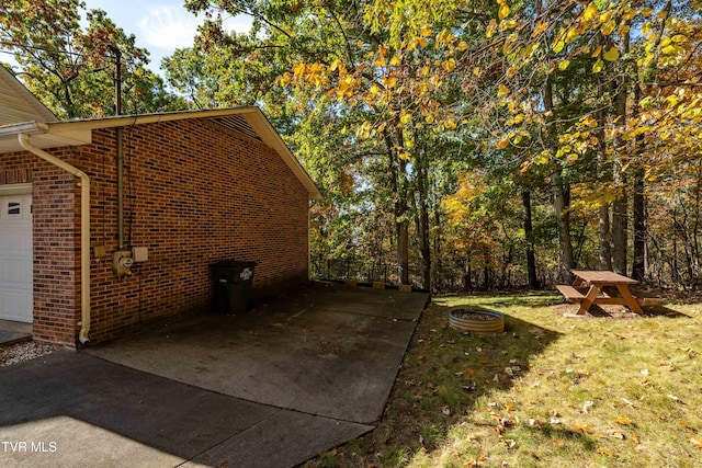 view of side of home with an outdoor fire pit, a garage, and a lawn