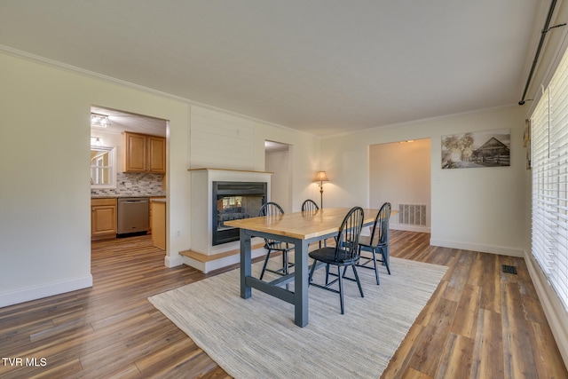 dining area with a wealth of natural light, crown molding, and dark hardwood / wood-style flooring