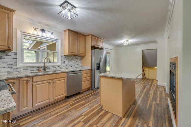 kitchen featuring appliances with stainless steel finishes, a center island, sink, and light stone counters