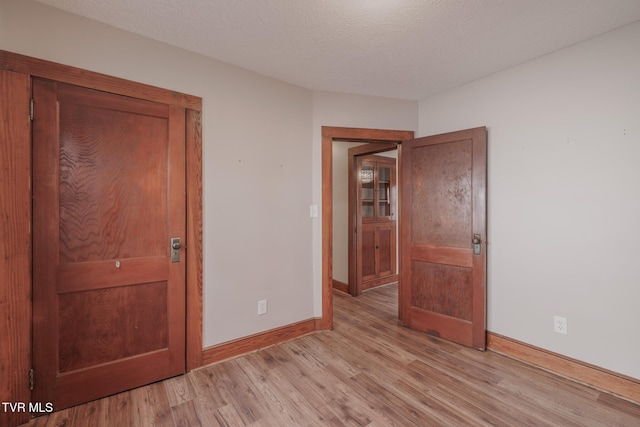 unfurnished bedroom with a textured ceiling and light wood-type flooring