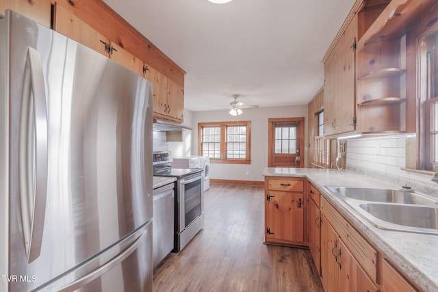 kitchen featuring appliances with stainless steel finishes, sink, light wood-type flooring, and decorative backsplash