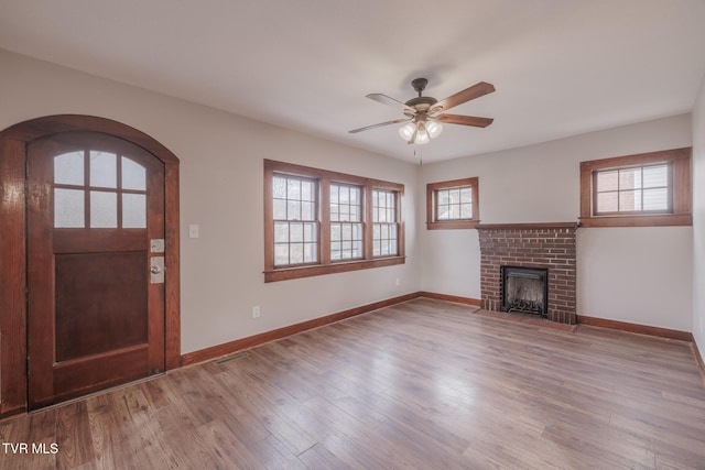 unfurnished living room featuring a brick fireplace, ceiling fan, and light hardwood / wood-style flooring