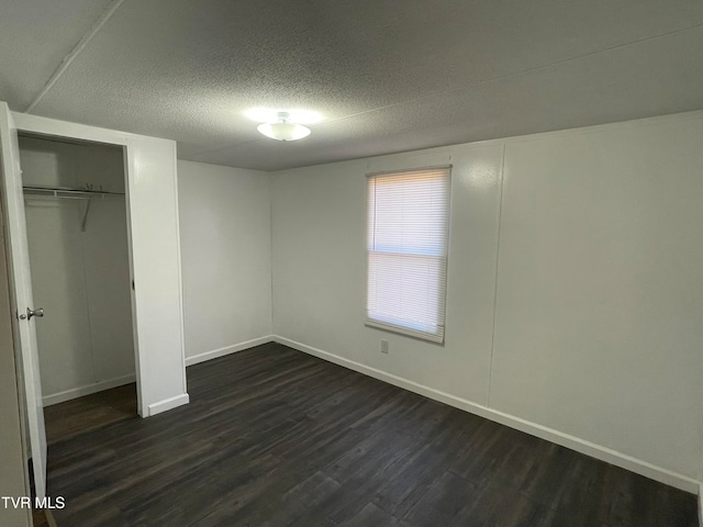 unfurnished bedroom featuring a textured ceiling and dark wood-type flooring