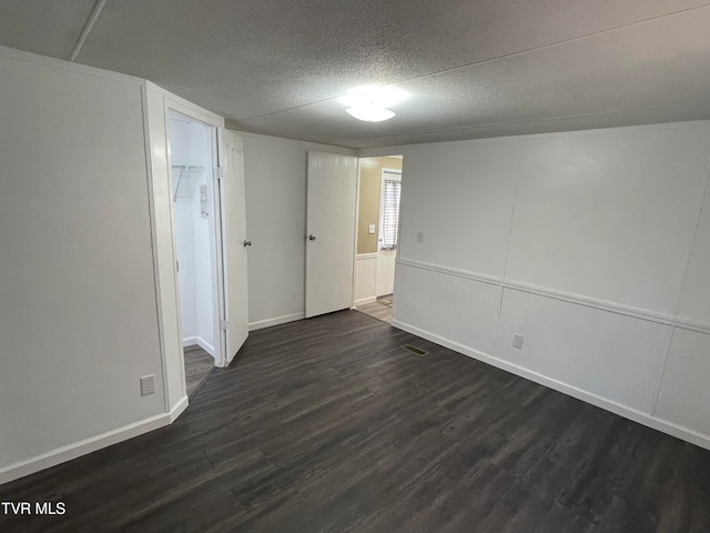 empty room featuring a textured ceiling and dark hardwood / wood-style flooring