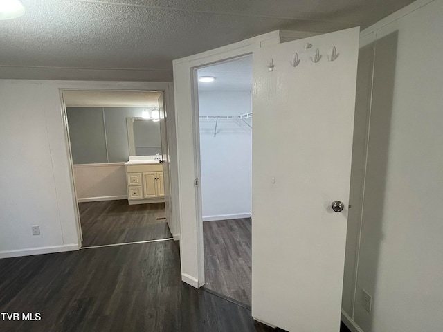 corridor featuring a textured ceiling and dark hardwood / wood-style flooring