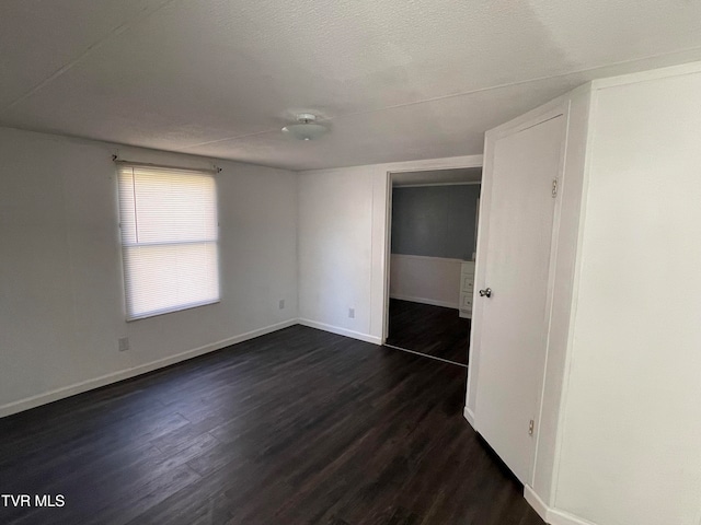 unfurnished room featuring a textured ceiling and dark hardwood / wood-style flooring