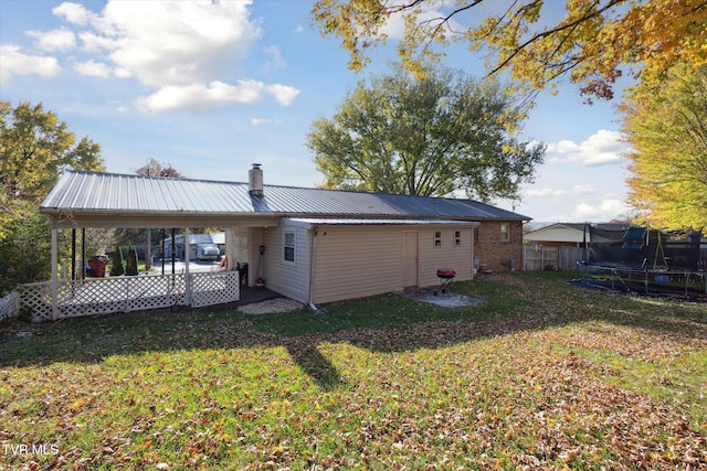 rear view of property with a patio area, a lawn, and a trampoline