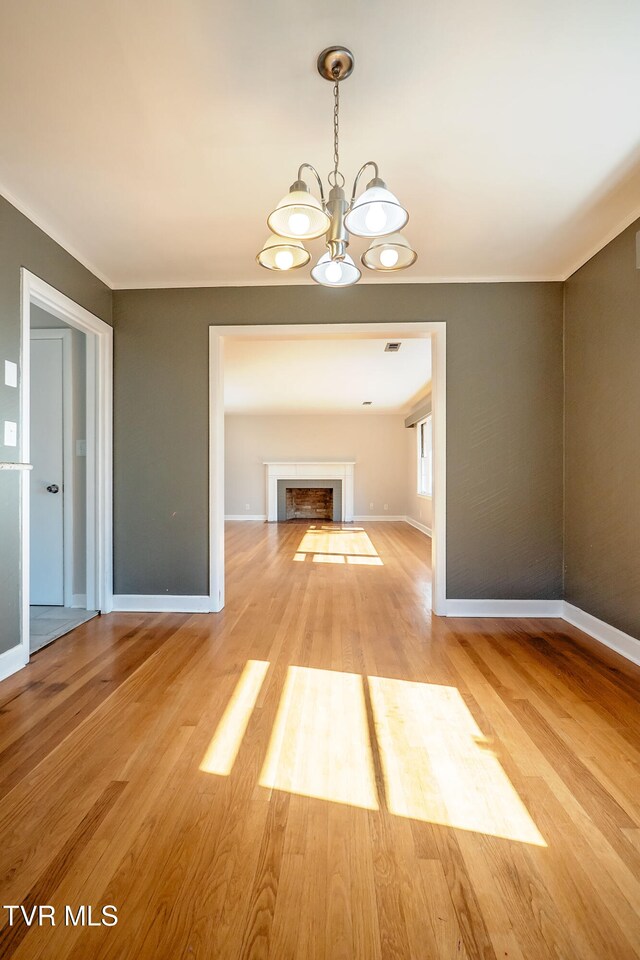 unfurnished living room with a chandelier and light hardwood / wood-style flooring