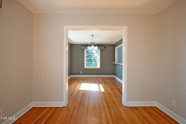 unfurnished dining area featuring an inviting chandelier and light hardwood / wood-style flooring