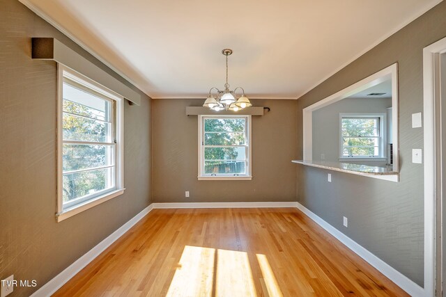 unfurnished dining area featuring light wood-type flooring, a notable chandelier, and plenty of natural light