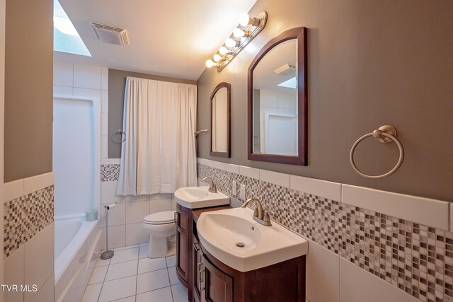 bathroom with toilet, a tub to relax in, tile walls, and tile patterned flooring