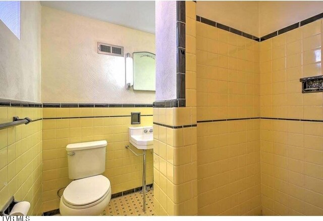 bathroom with toilet and tile walls