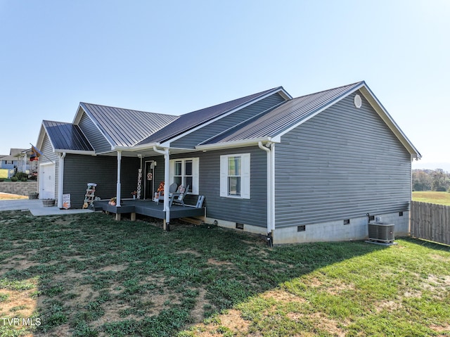 view of front of house with a front yard, a wooden deck, and central AC unit