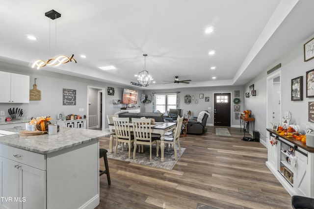 dining room featuring ceiling fan, a raised ceiling, and dark hardwood / wood-style flooring