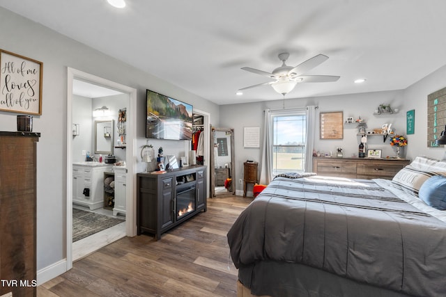 bedroom with ensuite bath, dark wood-type flooring, a closet, and ceiling fan