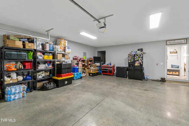 garage featuring a garage door opener and black fridge with ice dispenser