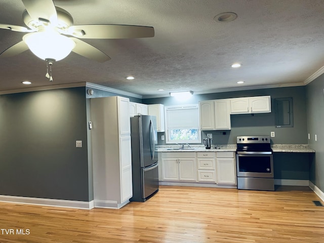 kitchen featuring light wood-style flooring, stainless steel appliances, white cabinets, crown molding, and baseboards