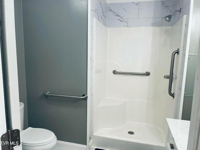 bathroom with toilet, vanity, and tiled shower