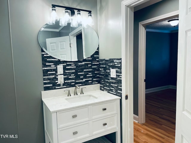 bathroom with vanity, crown molding, wood-type flooring, and tasteful backsplash