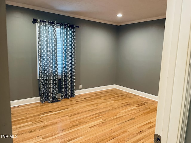 spare room featuring wood finished floors, baseboards, and ornamental molding