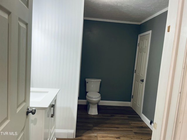 bathroom featuring toilet, wood finished floors, a textured ceiling, baseboards, and vanity