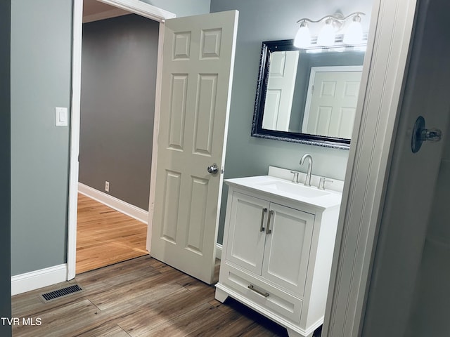 bathroom with baseboards, visible vents, wood finished floors, and vanity