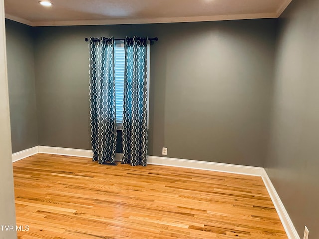 empty room featuring crown molding and light wood-type flooring