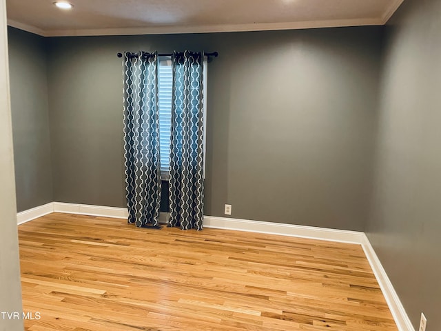 spare room with light wood-type flooring, baseboards, and ornamental molding