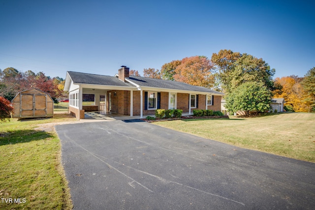 ranch-style house featuring a carport, a storage unit, and a front lawn