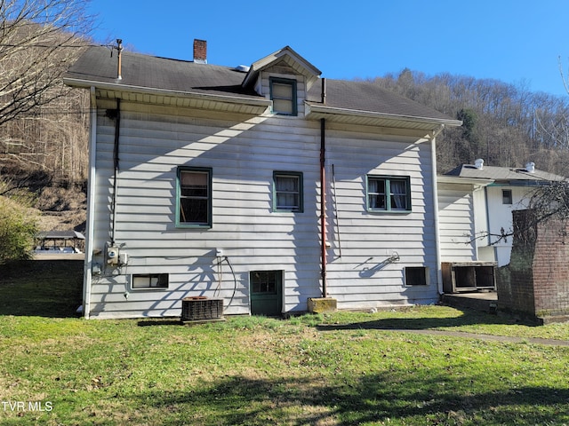 back of house with central AC and a lawn