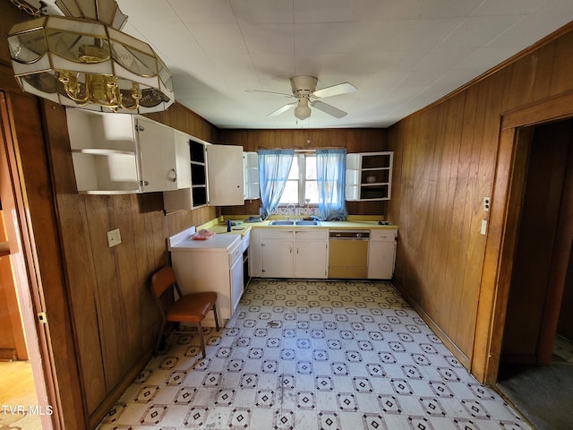 kitchen featuring white cabinetry, ceiling fan, wood walls, and dishwasher