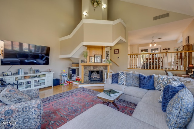 living room with a high ceiling, a fireplace, wood-type flooring, and a chandelier