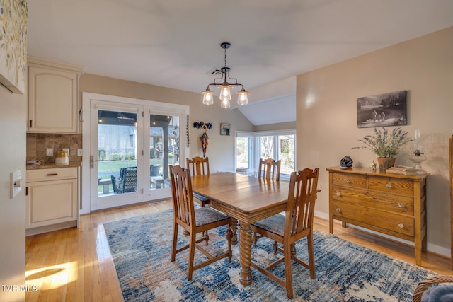 dining space with vaulted ceiling, light hardwood / wood-style flooring, and a notable chandelier