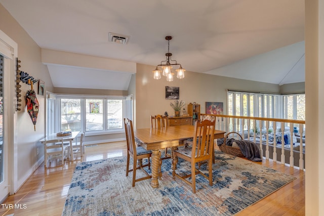 dining space with lofted ceiling, a notable chandelier, and light hardwood / wood-style floors