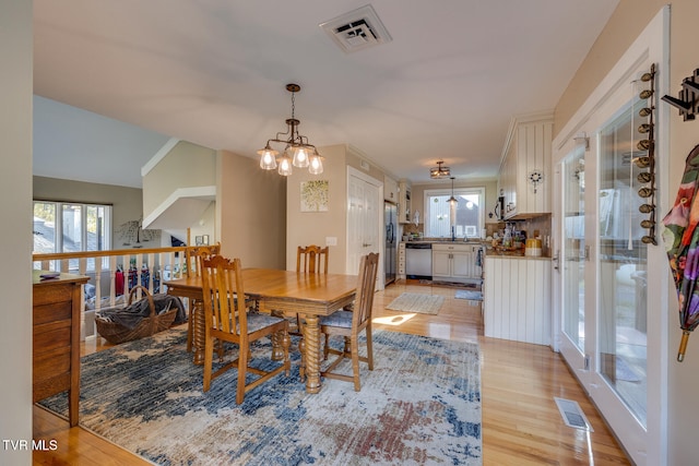 dining room with light hardwood / wood-style floors and a notable chandelier